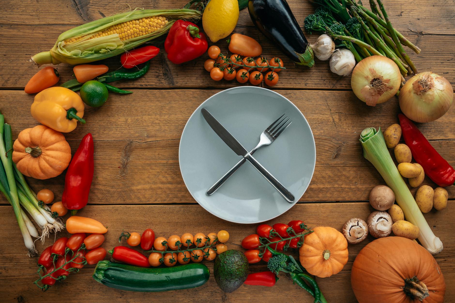 knife and fork on a ceramic plate surrounded by assorted vegetables